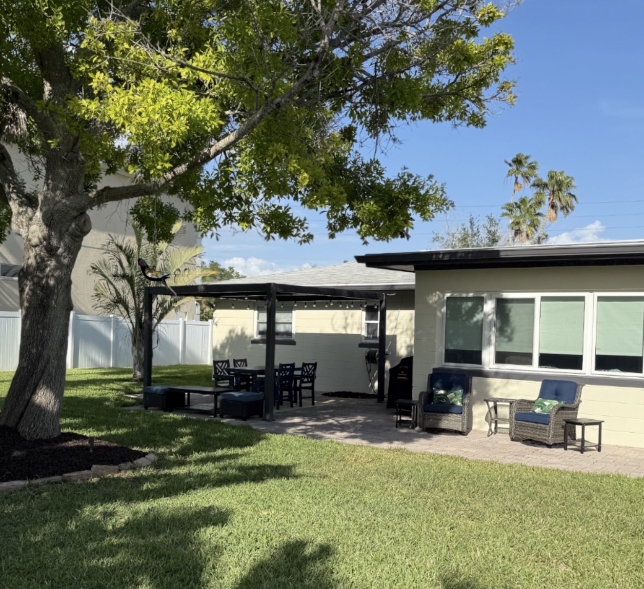 Backyard pergola with dining table for six and shaded seating under a mature tree