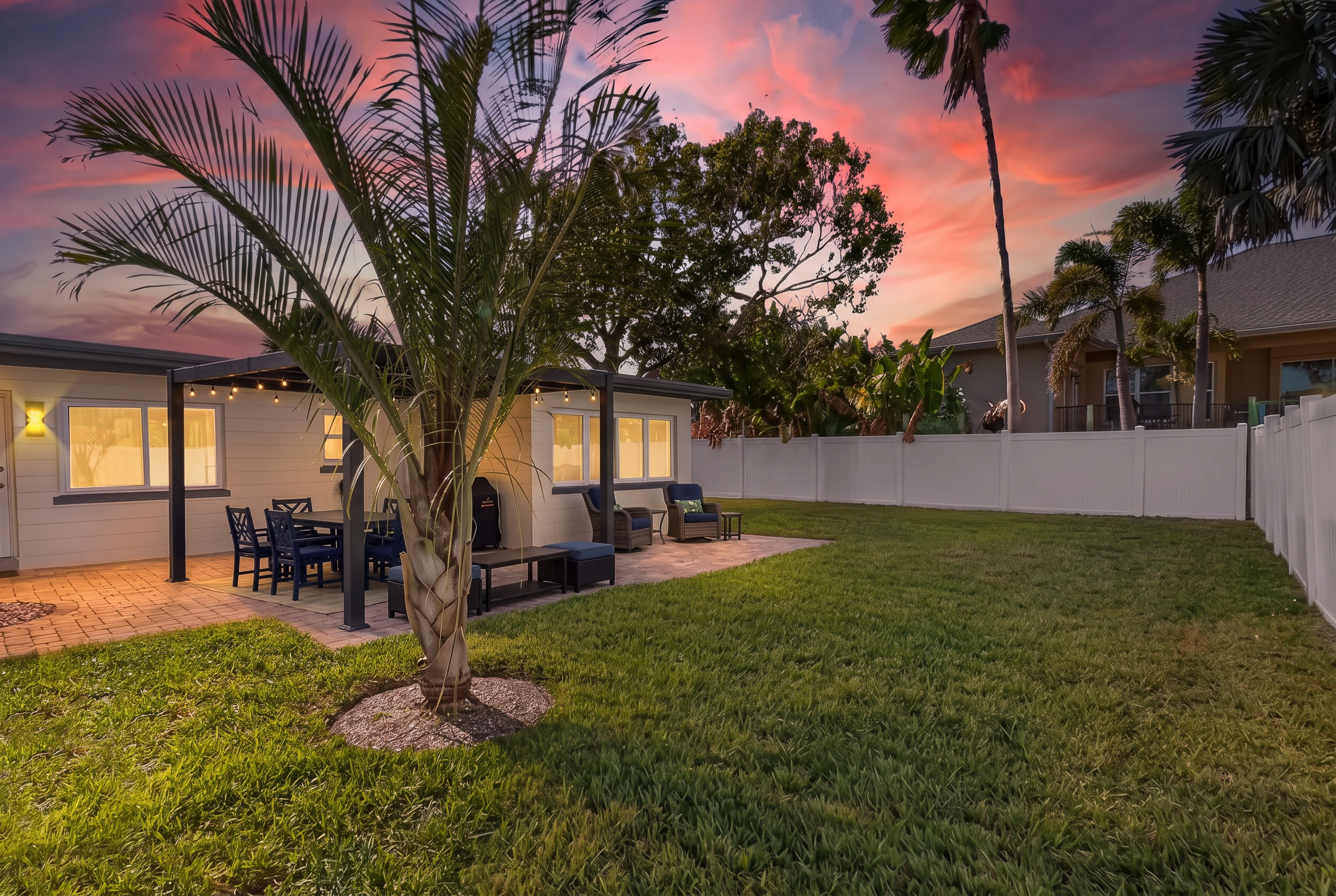 Backyard at twilight with palms silhouetted against a pink Florida sky