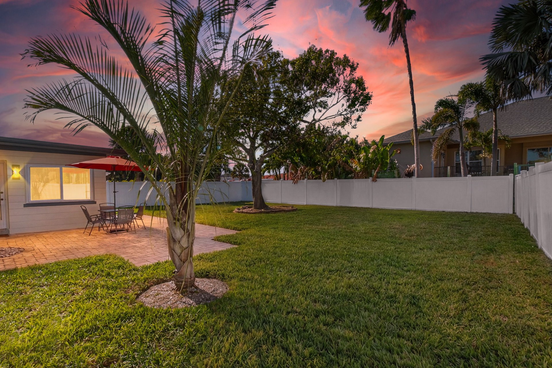 Backyard at twilight with palms silhouetted against a pink Florida sky